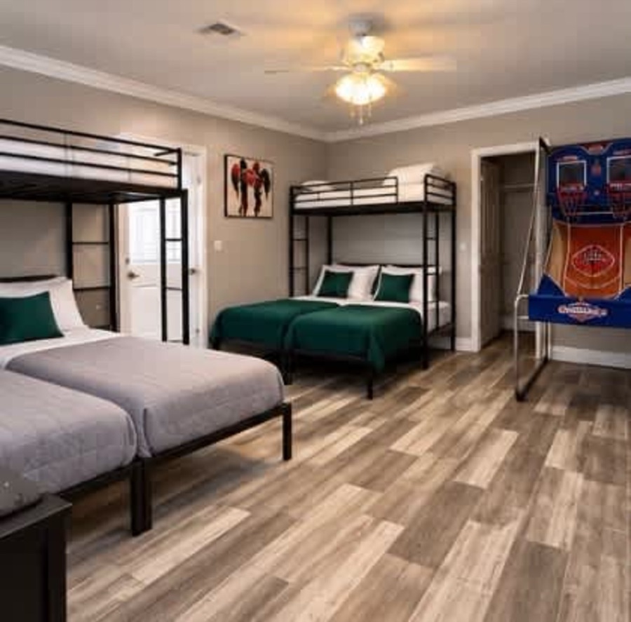 The bunk room: metal bunk frames with green and white bedding, and a two-hoop basketball arcade machine against the far wall.